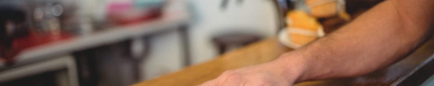 Close-up of waiter cleaning counter with cloth at cafe