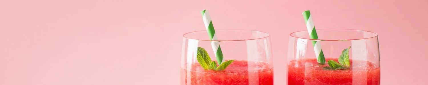 Watermelon smoothie with slice of fruit and leaf of mint over pink background